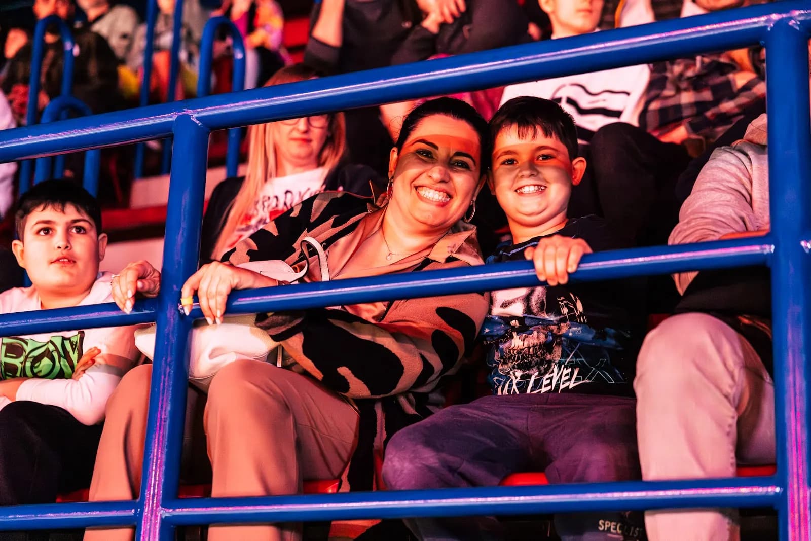 A mum and her two boys cheering at the railing during a Masters of Dirt show in Milan