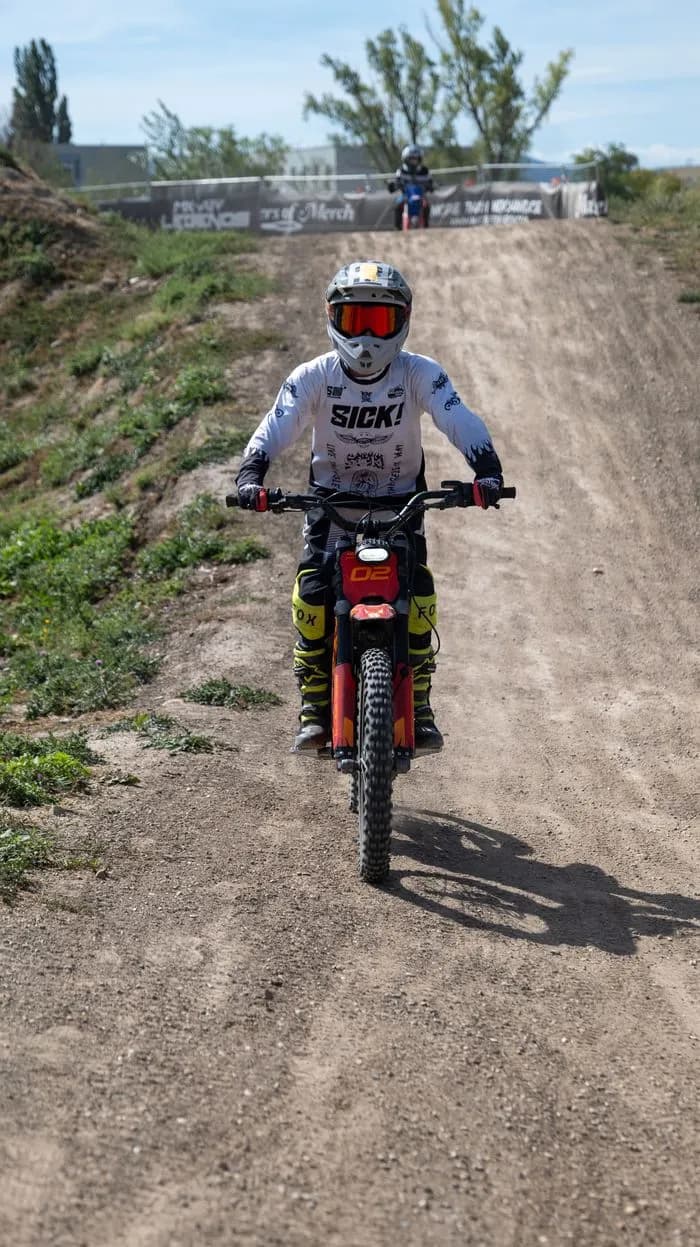 Young rider in full gear riding uphill on the kids track