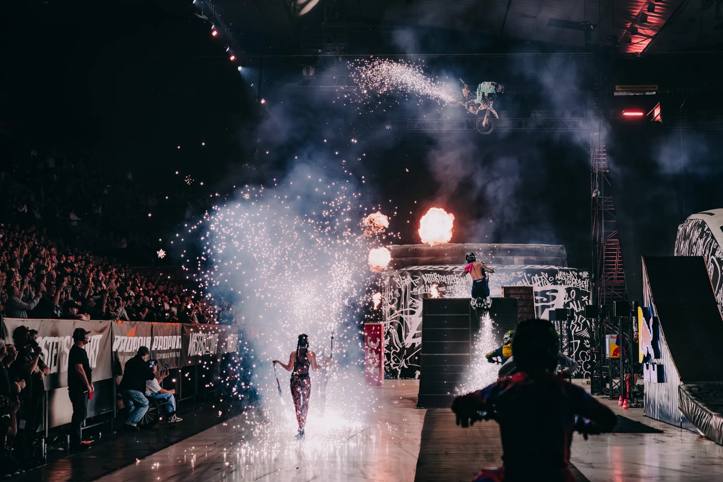 Pyro and a shower of sparks at Wiener Stadthalle in Vienna, an FMX rider mid-air